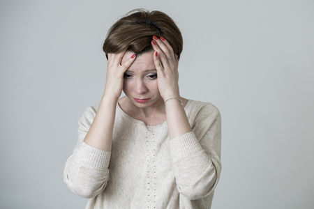 young pretty and sad red hair woman looking worried and depressed crying and suffering headache and migraine pain and depression in life problem concept isolated on even backgroundの写真素材