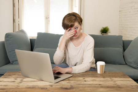 young attractive and busy woman at home sofa couch doing some laptop computer work in stress looking worried in entrepreneur lifestyleの写真素材