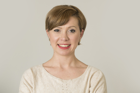 portrait of young happy and pretty red hair woman on her 30s in sweet smile and positive face expression looking to camera isolated on even background in cheerful emotion and female success conceptの写真素材