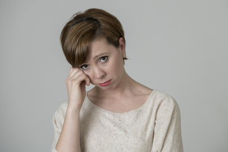 young pretty and sad red hair woman looking worried and depressed crying and suffering pain and depression in life problem concept isolated on even background studio portraitの写真素材