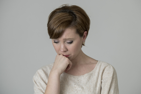 young pretty and sad red hair woman looking worried and depressed crying and suffering pain and depression in life problem concept isolated on even background studio portraitの写真素材
