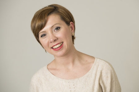 portrait of young happy and pretty red hair woman on her 30s in sweet smile and positive face expression looking to camera isolated on even background in cheerful emotion and female success conceptの写真素材