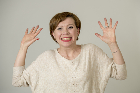 portrait of young happy and pretty red hair woman on her 30s in sweet smile excited posing with hands up funny and playful  looking to camera isolated on even background in cheerful emotionの写真素材