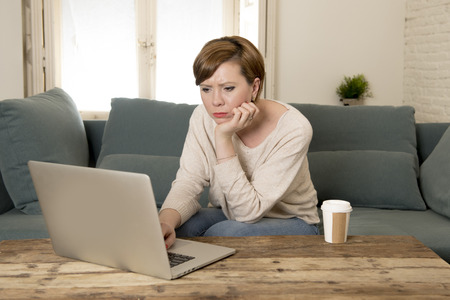 young attractive and busy woman at home sofa couch doing some laptop computer work in stress looking worried in entrepreneur lifestyleの写真素材