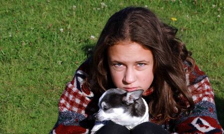 Girl in a bright sweater playing with a small dogの写真素材