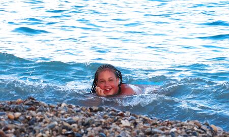 The girl lies on the shore of a calm sea in the waterの写真素材