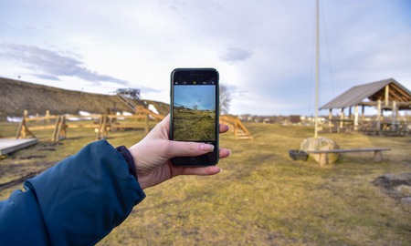 Rural landscape is displayed on the smartphone screen in the hand of a girl in winterの写真素材
