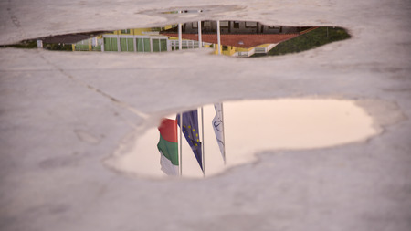 Reflection of the flags of Bulgaria and the European Union in a puddle after the rainの写真素材
