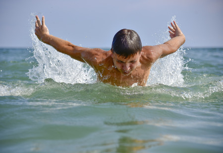 Swimmer in the open sea directly on camera half visible from the water the sun is shining seaの写真素材