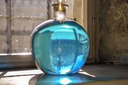 Round bottle, flask with blue liquid on the window medievalの写真素材
