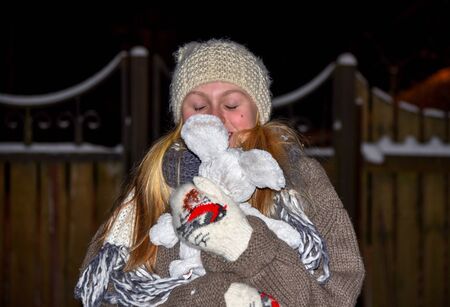 Girl in the winter night on the street freezing white caps and mittens portrait close-upの写真素材