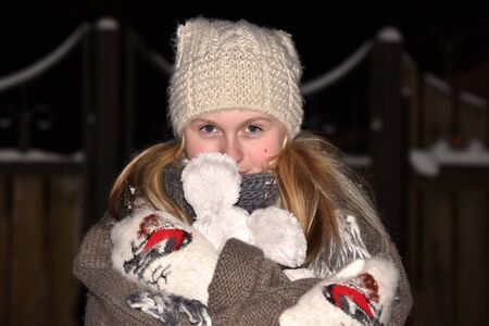 Girl in the winter night on the street freezing white caps and mittens portrait close-upの写真素材