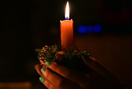 divination ritual girl's hands holding a burning candle in the dark lightの写真素材