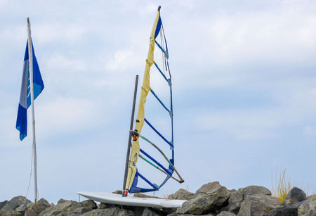 Surfing with a ragged sail on the rocky shoreの写真素材