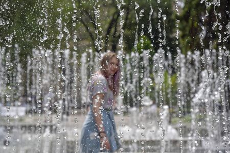 A young girl and a jet of fountain water backの写真素材