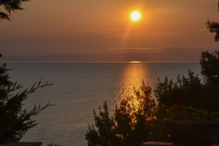 The sun sets over the sea dark waterの写真素材