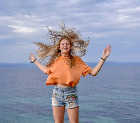 Girl standing on a cliff above the sea red blue irangeの写真素材