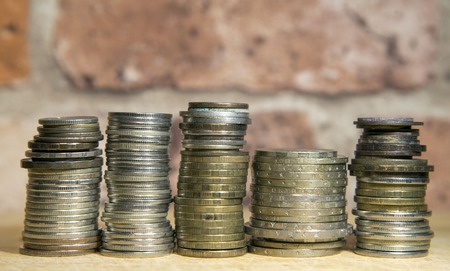 Stacks of coins and a vintage brick wallの写真素材