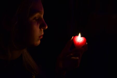 The girl in the dark looking at a lighted candle divinationの写真素材