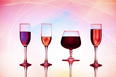 Four wine glasses of water are on the table, behind a colorful background.Glasses reflectedの写真素材