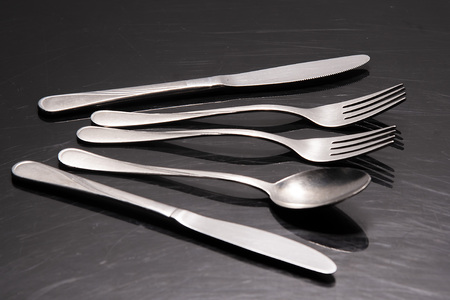 Two silver knives, two forks and a spoon are on the tableの写真素材