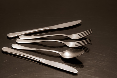 Two silver knives, two forks and a spoon are on the tableの写真素材