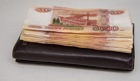 A pack of five thousand bills lies on a brown purse, on a gray background. Brounの写真素材