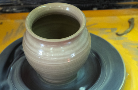 Master class on making a ceramic pot with a Potters wheel. The pottery is rotating around its axis.の写真素材