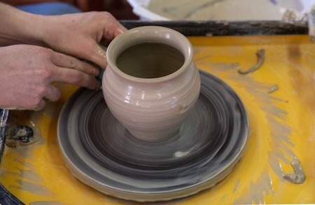 Master class on making a ceramic pot with a Potters wheel. The pottery is rotating around its axis.の写真素材