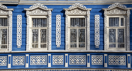 The blue wall of the house with Windows and beautiful carved wooden frames.の写真素材