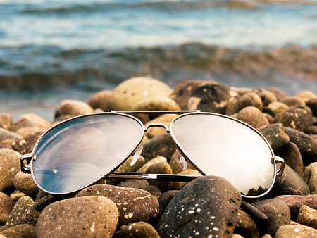 Sunglasses lie on the pebble beach.の写真素材