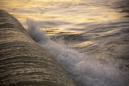Large waves and sea foam illuminated by the evening sun. The water shines like metal.の写真素材
