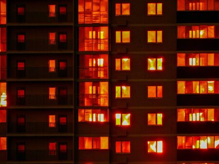 Night snapshot. Dark residential high-rise buildings, in which red light Windows and balconies. Contrast photography.の写真素材