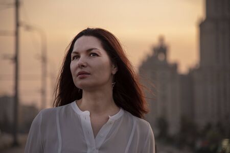 Portrait of a middle-aged woman in profile in a white blouse with her hair down. Against the...
