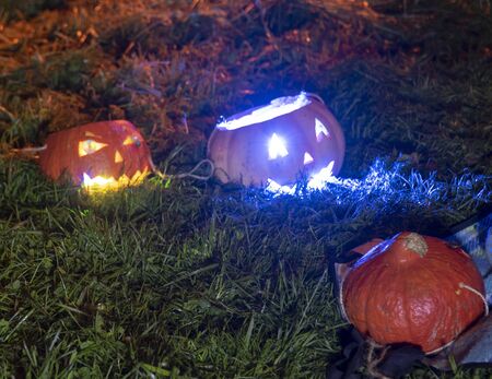 Photo in darkness.Three pumpkins lie on the ground.Have two Shine eyes and his mouth.の写真素材