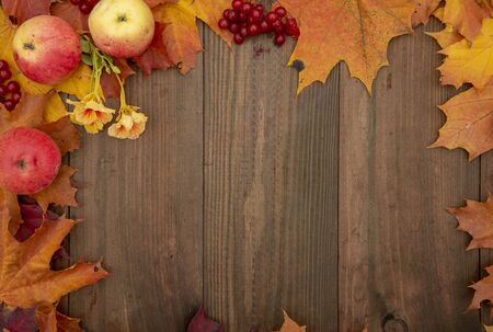 Frame of autumn bright leaves, apples, berries and flowers on a wooden background.Flat Lay, Top Viewの写真素材