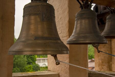 Bells of various sizes hang from a thick wooden beam. The monastery bell tower.の写真素材