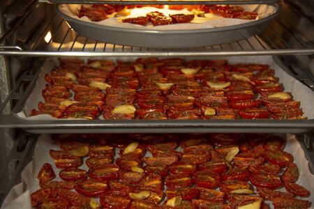 The process of cooking dried tomatoes.Vegetables with spices and garlic in the oven on trays on three levels.の写真素材