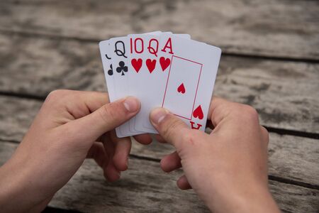 Playing cards in human hands on a gray wooden background.の写真素材