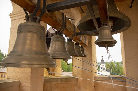 Bells of various sizes hang from a thick wooden beam. The monastery bell tower.の写真素材