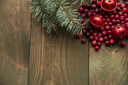 Blue spruce branch, cranberries and red Christmas bells on a wooden background.The view from the top. flat lay. Space for textの写真素材