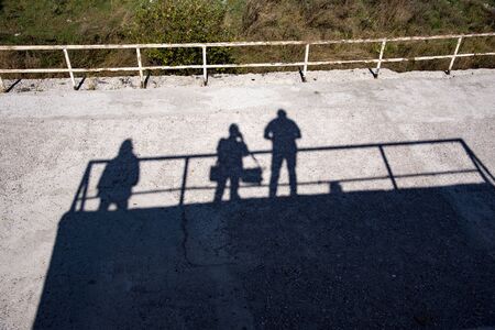 On the asphalt Silhouettes and shadows of people standing on a hill in a bright Sunny day