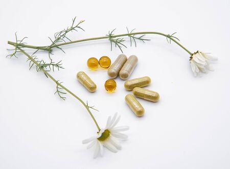 Two fresh chamomile medicinal and various pills and pills on a light background.の写真素材