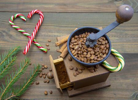 Hand grinder, fir branches, coffee beans and Christmas candy on a wooden background.の写真素材