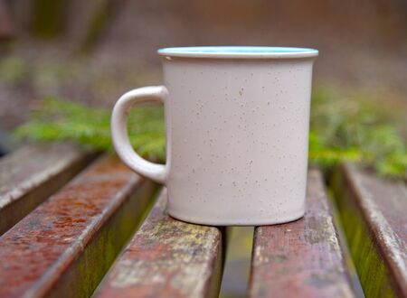 Ceramic mug on a wooden bench on a blurred background.の写真素材