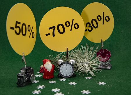 Small toy figures, Christmas decor with signs indicating the percentage of the sale on a green background. Christmas sale.の写真素材