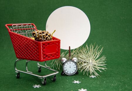Shopping cart with Christmas decor and an empty sign for the text. On green backgroundの写真素材