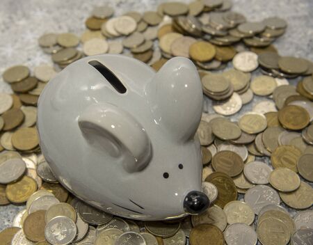 Gray mouse-piggy Bank on a pile of coins . Symbol of the year.の写真素材