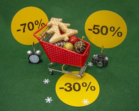 Christmas sale. Shopping cart with Christmas decor and signs indicating the percentage of sales. Conceptual photography.の写真素材