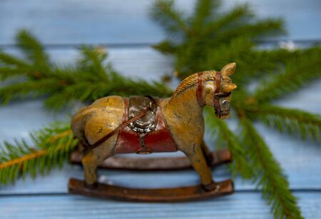Christmas toy rocking horse and spruce branches on a blue wooden background.の写真素材